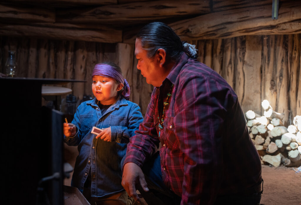 Navajo dad teaching son to light stove in a traditional Hogan