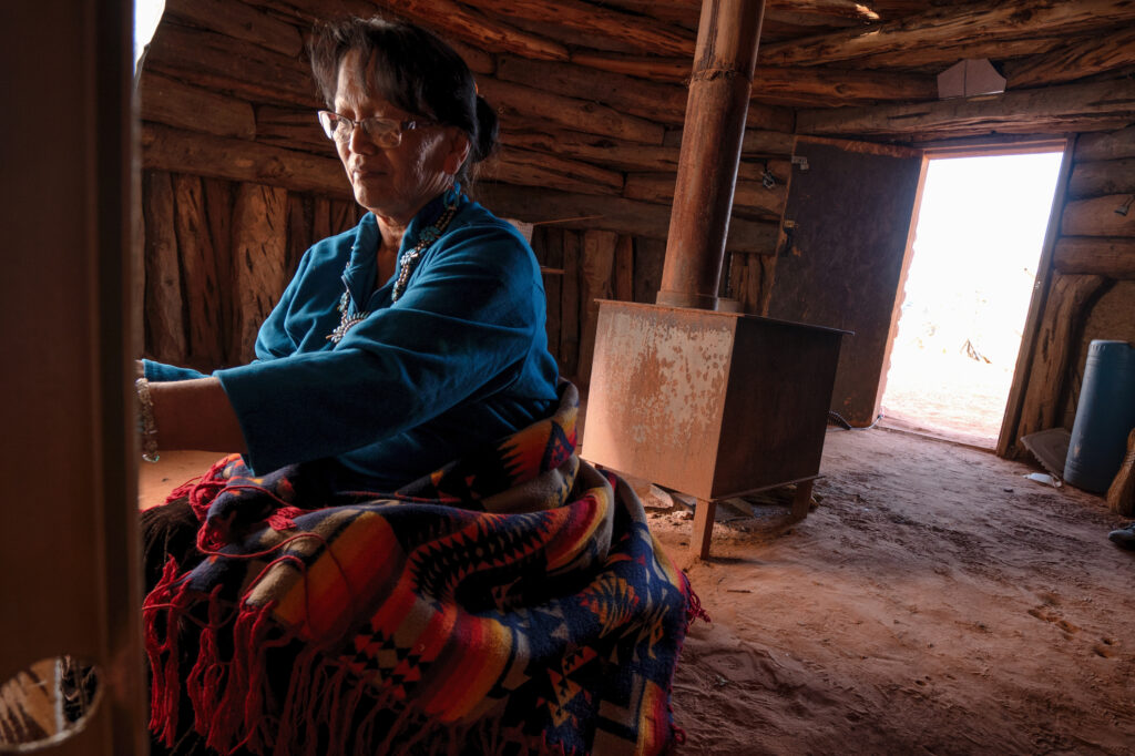 Elderly Native American Navajo Woman Weaving a Traditional Tribal Blanket on a loom inside a Hogan