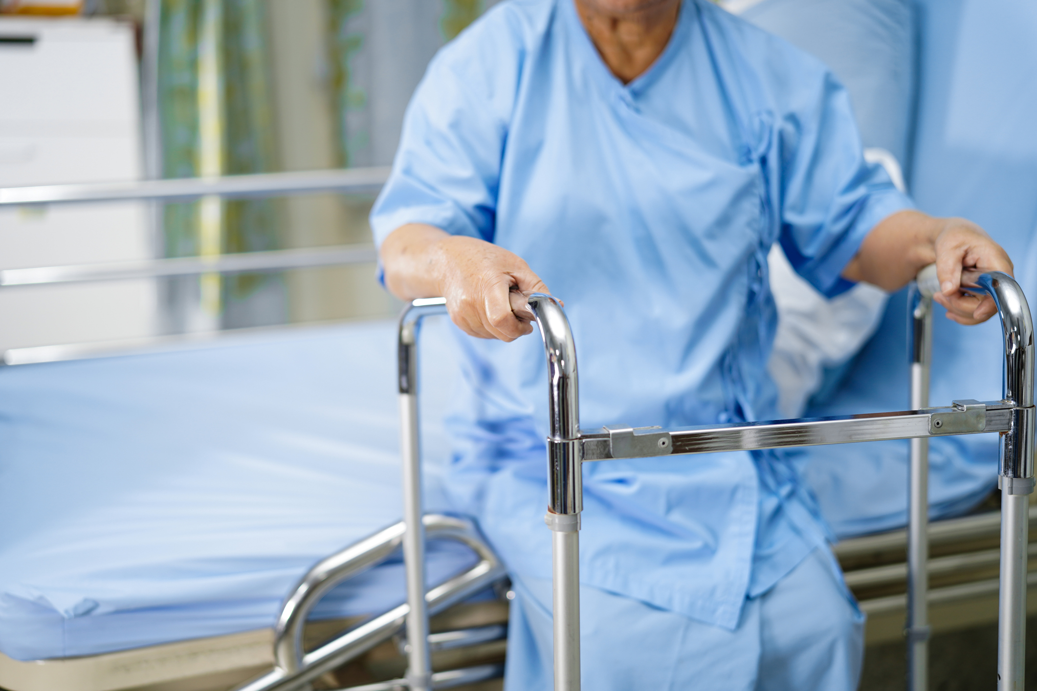 Elderly patient using a walker to get out of hospital bed